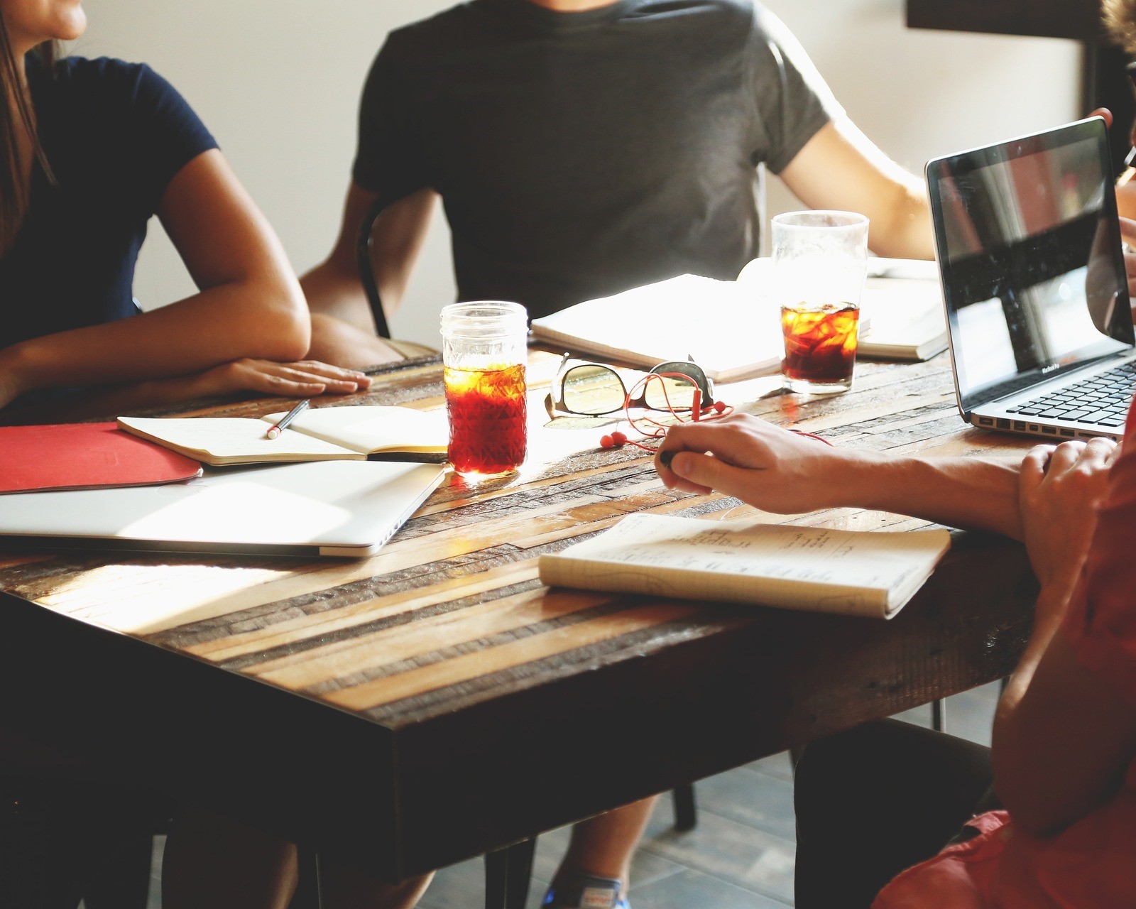 Group of people sitting around a table with note pads and laptops